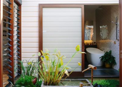 Breezway louvres in timber frame on left and bathtub in distance with views out onto Japanese garden