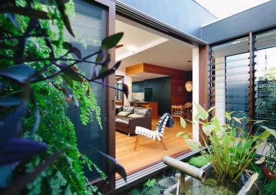 View of Japanese garden and living room with Breezway louvres in glass link